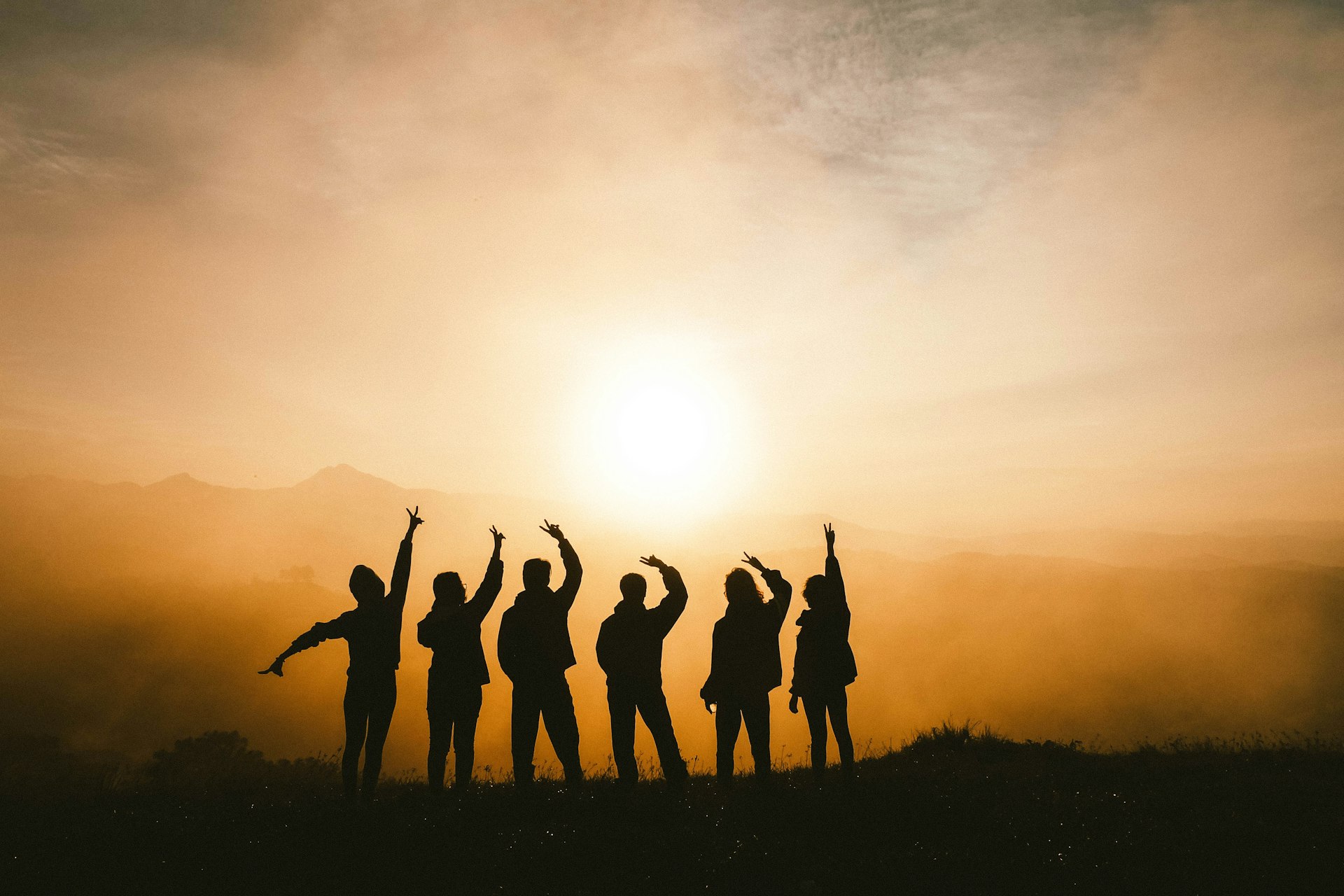silhouette de 6 personnes en train de se détendre en regardant les montagnes
